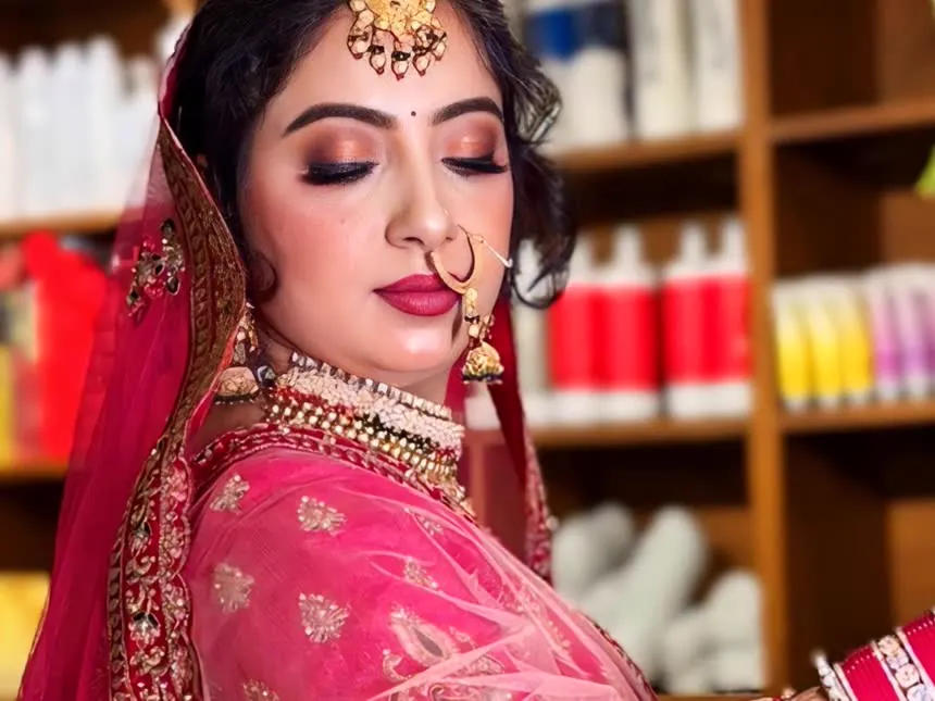 A bride in a pink lehenga in front of the product wall in our studio