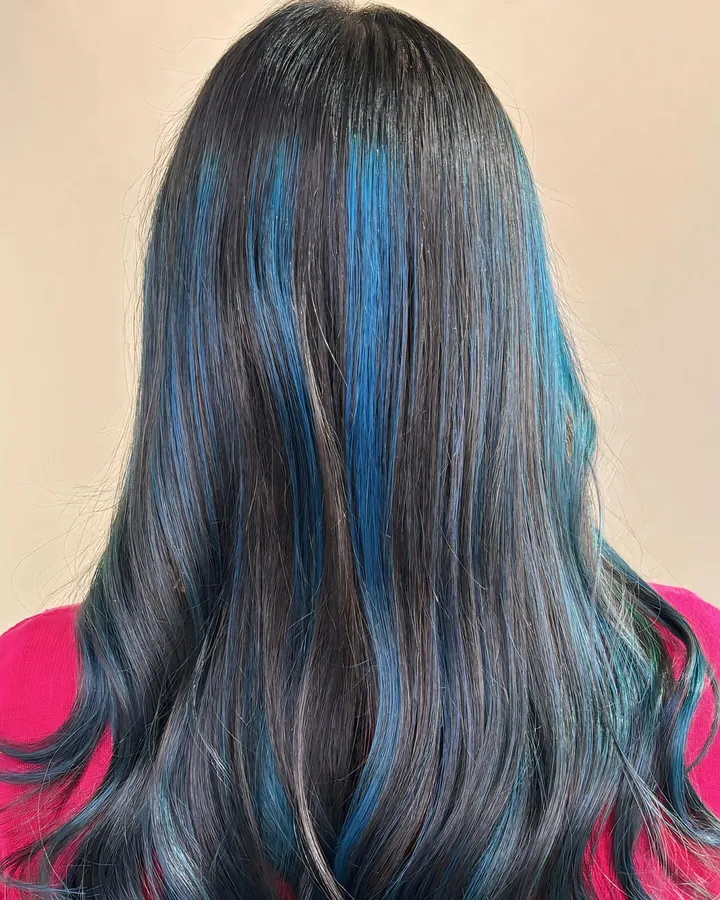Back view of long dark hair with blue and teal streaks running from the crown through the lengths.
