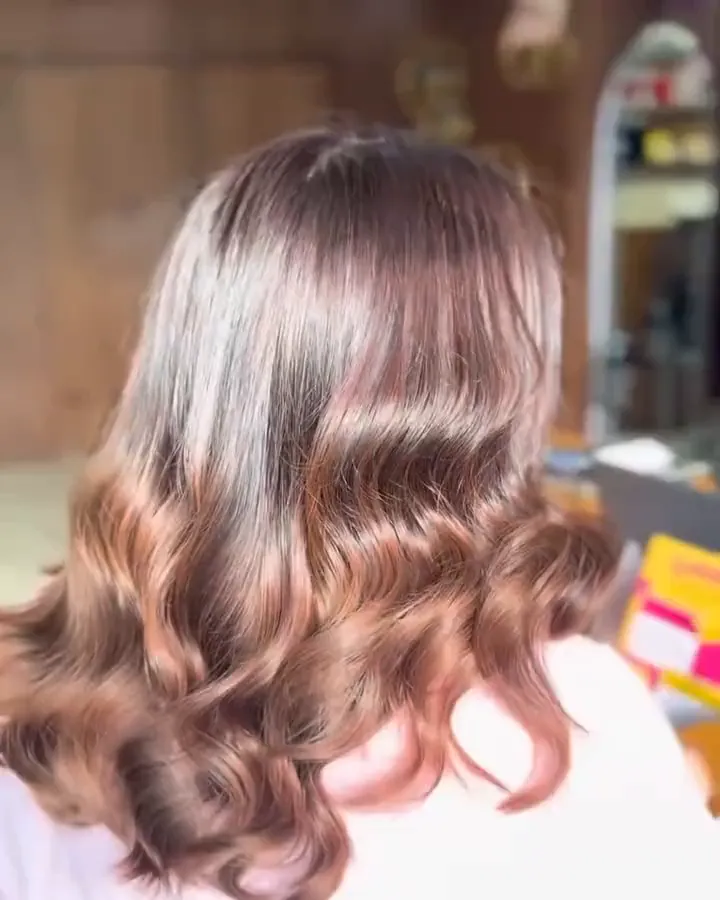 Back view of copper balayage in loose waves, seen from behind in the salon.