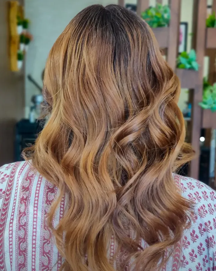Back view of honey gold balayage in loose waves reaching mid-back, with darker roots.