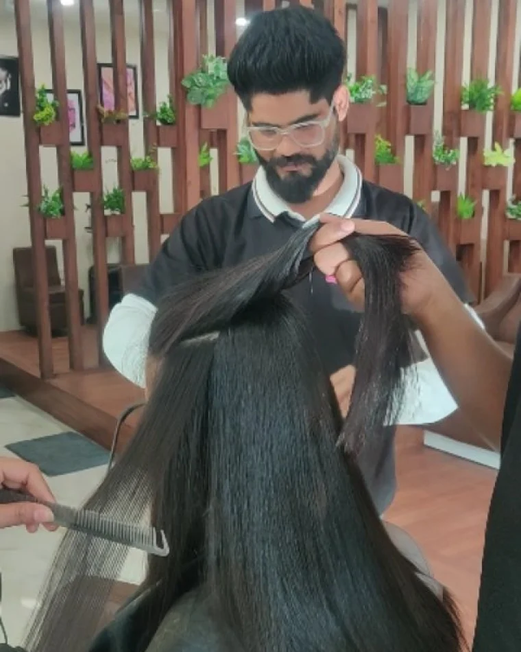 A stylist lifting a section of long straight hair to check it after the treatment.