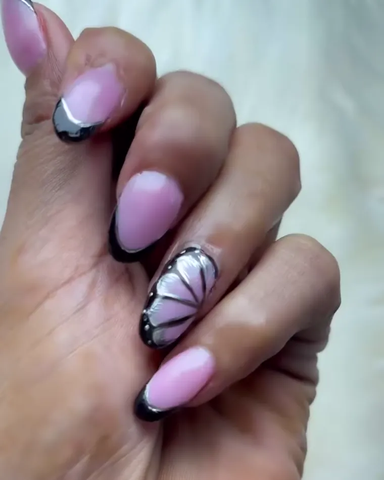 Pink almond nails with black tips and one nail hand-painted as a butterfly wing.