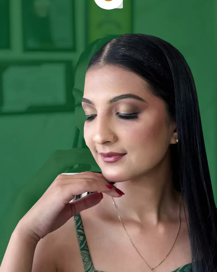 Fresh, glowing skin with a soft brown eye and a nude lip, eyes down, in a green saree.