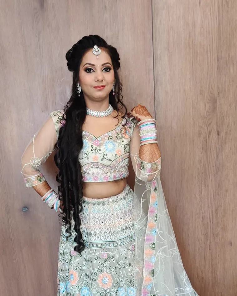 Pastel lehenga look with soft makeup, a small maang tikka and open braided hair.