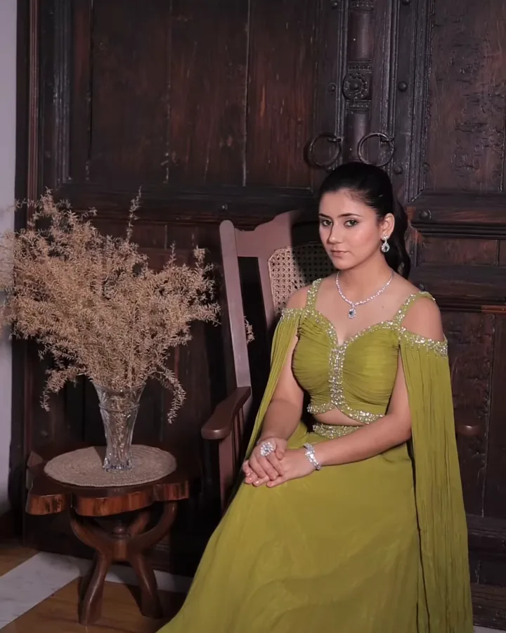 A lime-green outfit with fluted sleeves, seated in a carved chair, from our styled shoot.