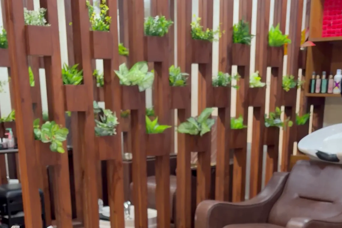The wooden planter partition inside the studio, with the wash basin and a wash chair behind it.