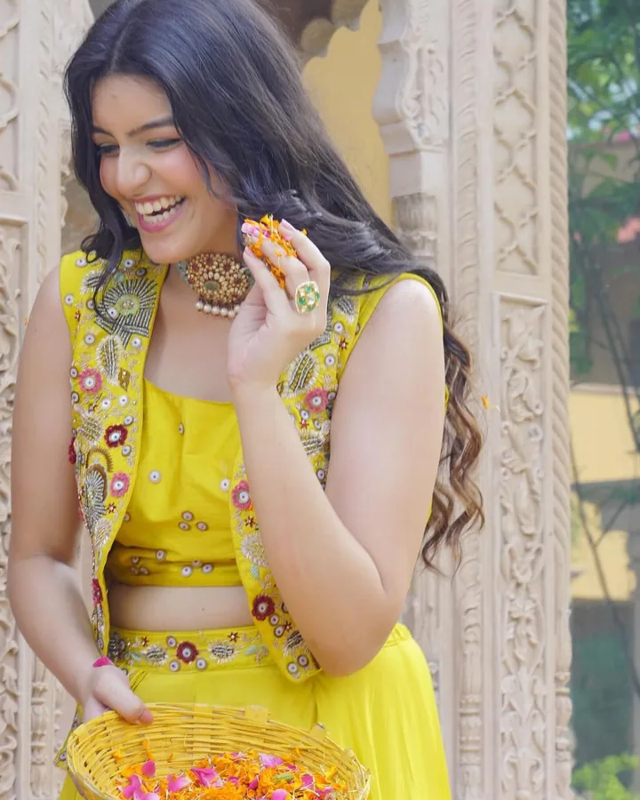 Haldi look from our styled shoot: laughing in a yellow embroidered jacket, a basket of marigold and rose petals in hand.