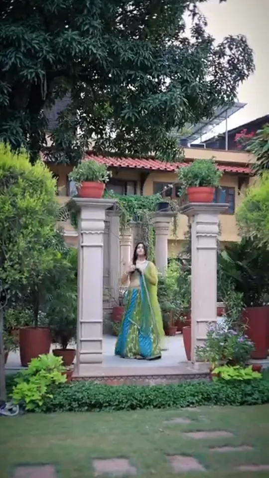 Mehendi look from our styled shoot: full length in a green and blue lehenga beside a courtyard pillar.