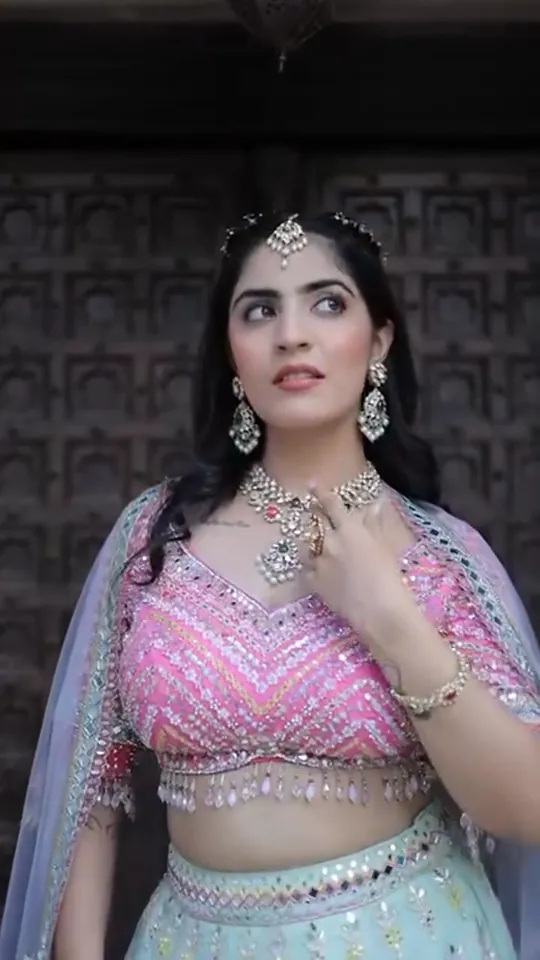 Haldi look from our styled shoot: a hot-pink mirror-work blouse and mint lehenga at a carved door.